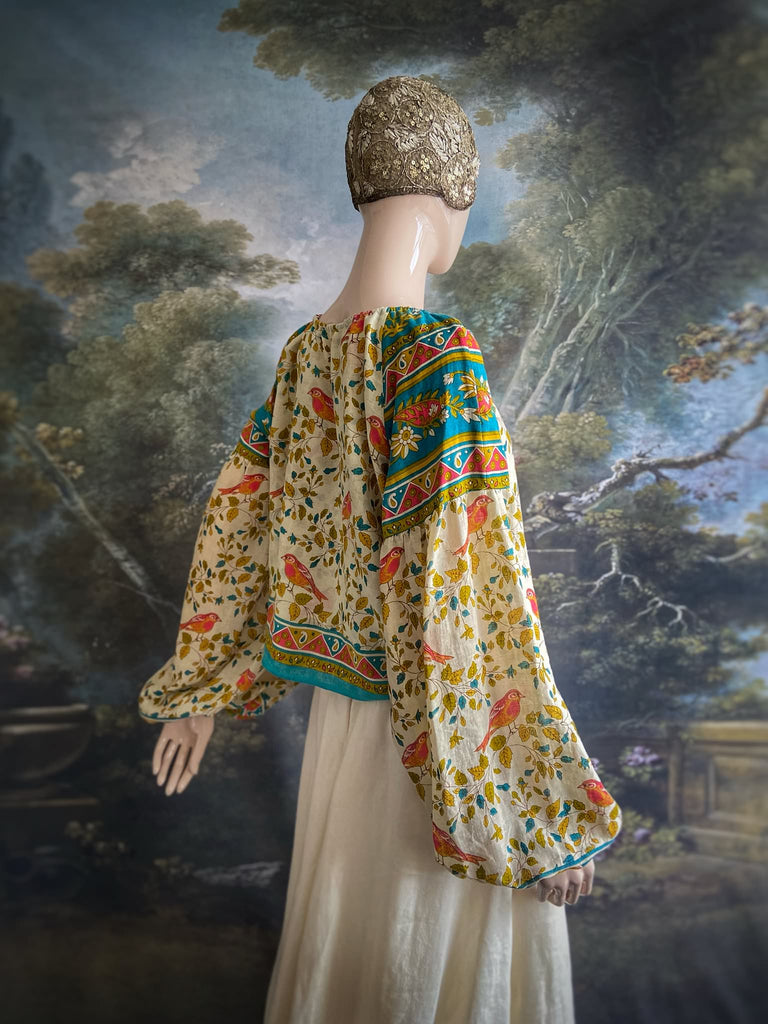 Coral, blue and ivory cotton muslin bird printed blouse with long full sleeves and adjustable drawstring neckline. Bohemian styles sustainably created from antique and vintage textiles by the Pavilion Parade studio. 