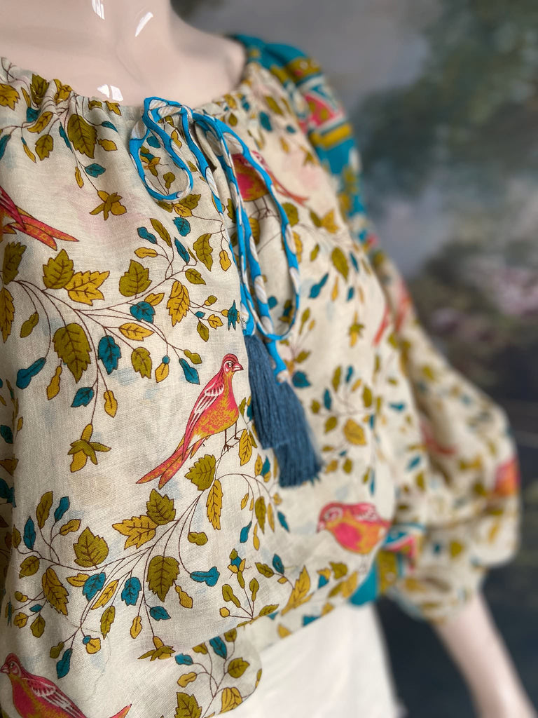 Coral, blue and ivory cotton muslin bird printed blouse with long full sleeves and adjustable drawstring neckline. Bohemian styles sustainably created from antique and vintage textiles by the Pavilion Parade studio. 