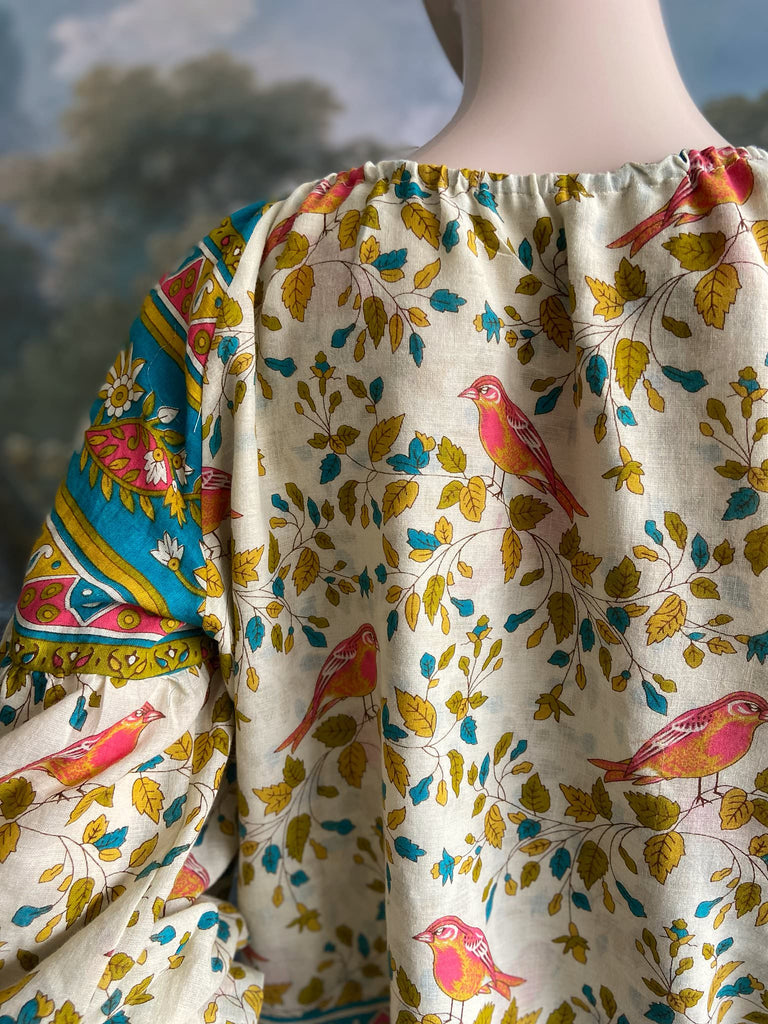 Coral, blue and ivory cotton muslin bird printed blouse with long full sleeves and adjustable drawstring neckline. Bohemian styles sustainably created from antique and vintage textiles by the Pavilion Parade studio. 