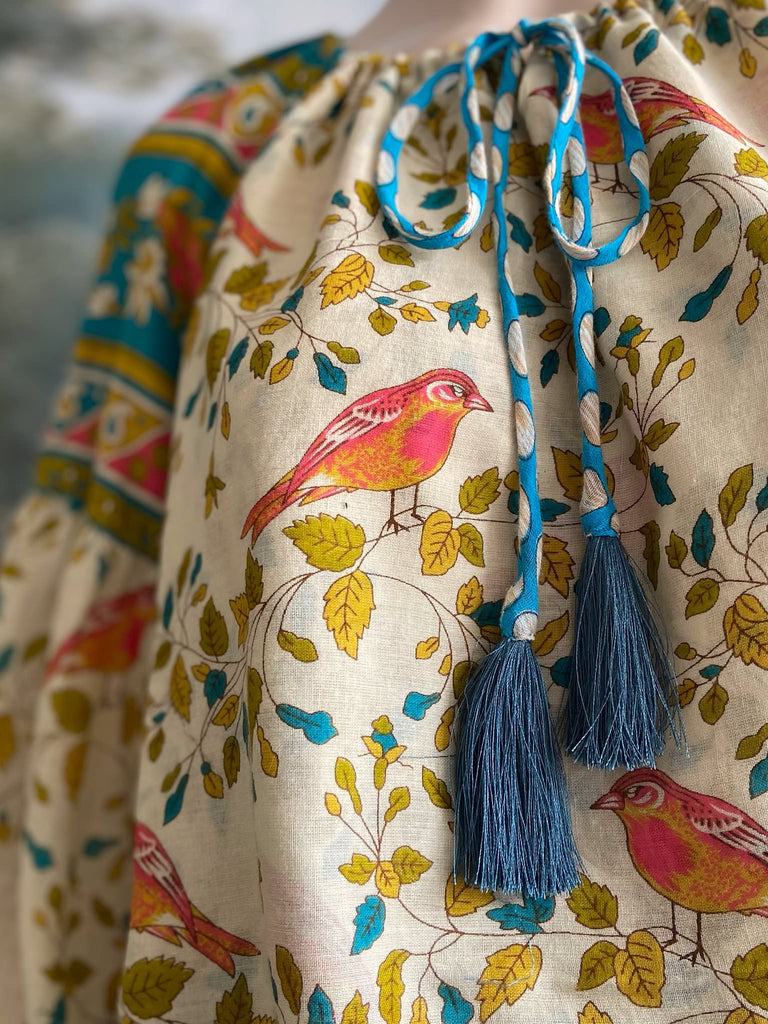 Coral, blue and ivory cotton muslin bird printed blouse with long full sleeves and adjustable drawstring neckline. Bohemian styles sustainably created from antique and vintage textiles by the Pavilion Parade studio. 