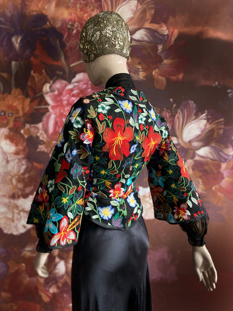 Frida Kahlo inspired embroidered silk and tulle bodice jacket with picture neckline and pagoda sleeves. Vivid black, red, green and blue floral. Flight of fancy from the Pavilion Parade studio. 