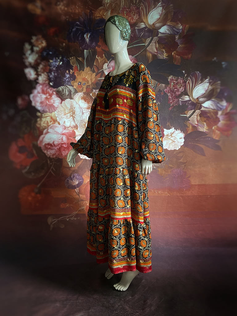Black, burnt orange, and chilli red silk georgette maxi dress with tassel drawstring neckline, long full sleeves and side pockets. Bohemian style sustainably created from vintage and antique textiles by the Pavilion Parade studio.