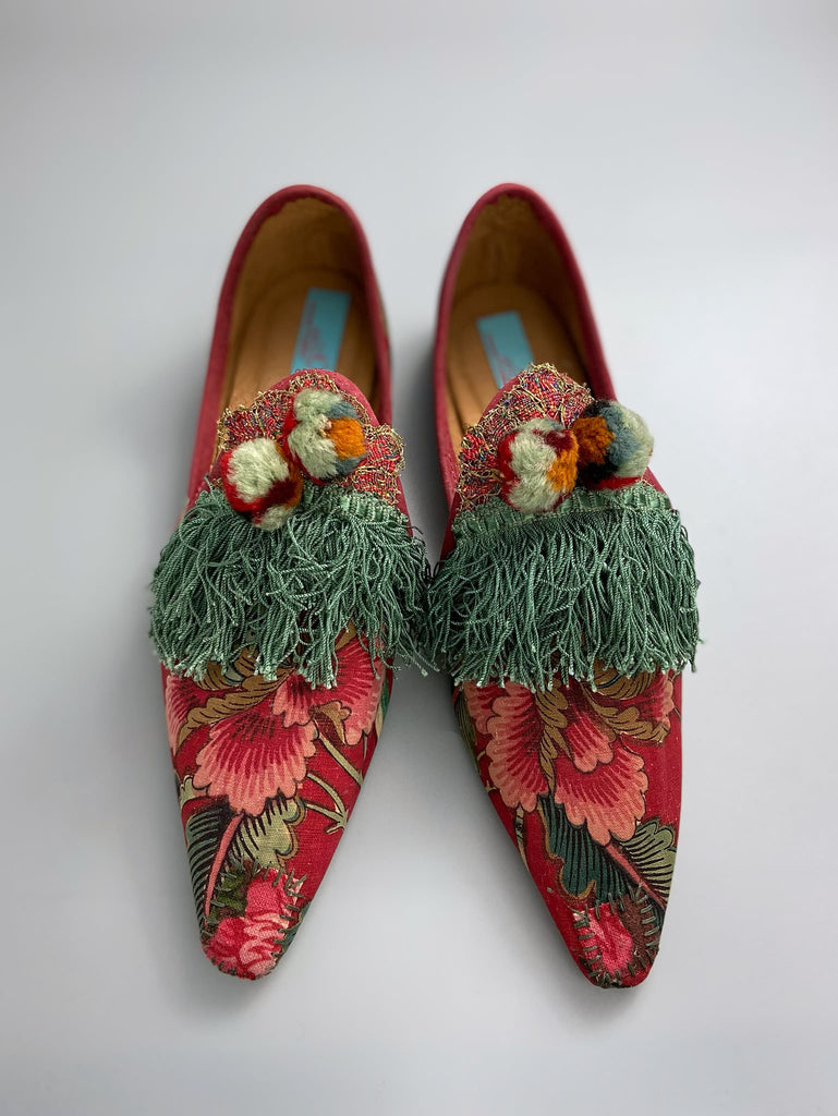 Vibrant floral Indienne toile pointed toe shoes in shades of red pink and green. Embellished with silk tassel fringe, metallic 1920s braid and antique wool pom pom tassels. Bohemian styles sustainably created from antique textiles by the Pavilion Parade studio.