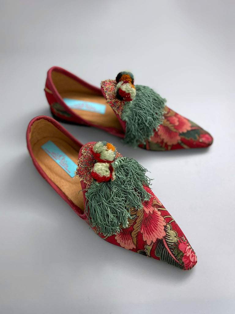 Vibrant floral Indienne toile pointed toe shoes in shades of red pink and green. Embellished with silk tassel fringe, metallic 1920s braid and antique wool pom pom tassels. Bohemian styles sustainably created from antique textiles by the Pavilion Parade studio.
