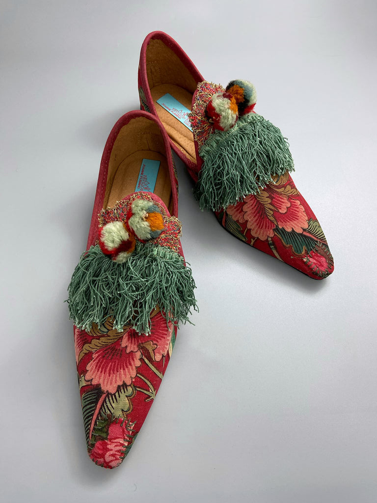Vibrant floral Indienne toile pointed toe shoes in shades of red pink and green. Embellished with silk tassel fringe, metallic 1920s braid and antique wool pom pom tassels. Bohemian styles sustainably created from antique textiles by the Pavilion Parade studio.