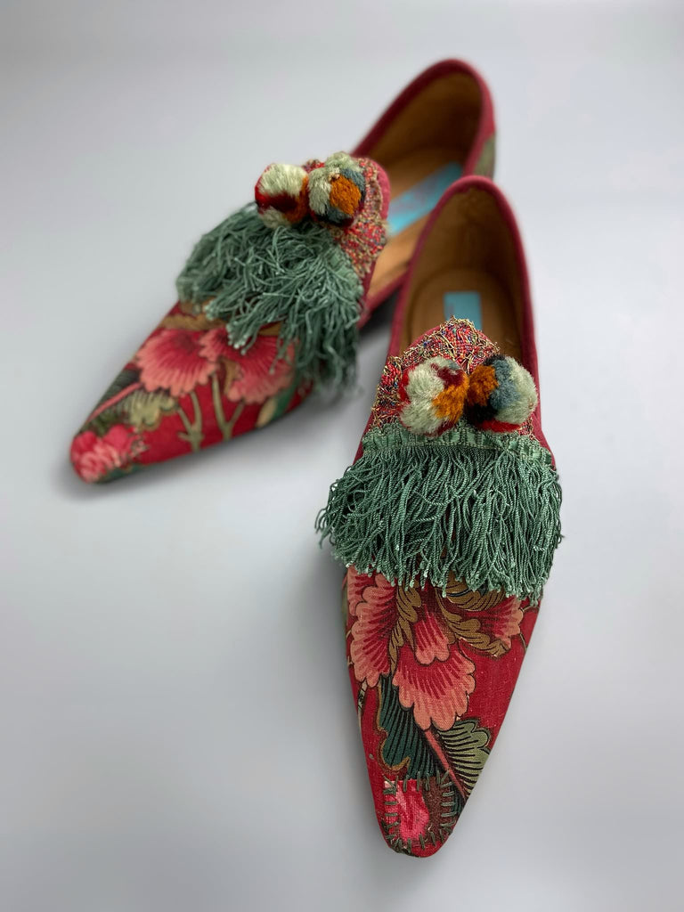 Vibrant floral Indienne toile pointed toe shoes in shades of red pink and green. Embellished with silk tassel fringe, metallic 1920s braid and antique wool pom pom tassels. Bohemian styles sustainably created from antique textiles by the Pavilion Parade studio.