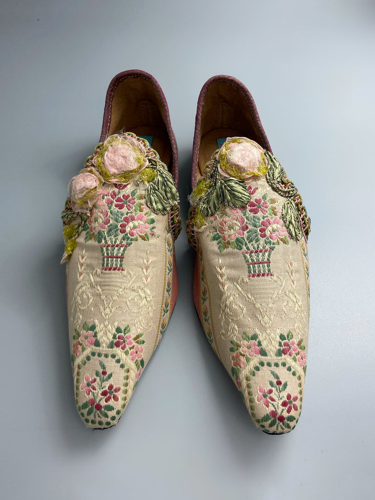 Dusty pink and cream silk pointed toe shoes with timeworn ribbon roses in the Georgian style. Embellished with antique braids. Bohemian styles sustainably created from antique textiles by Pavilion Parade.