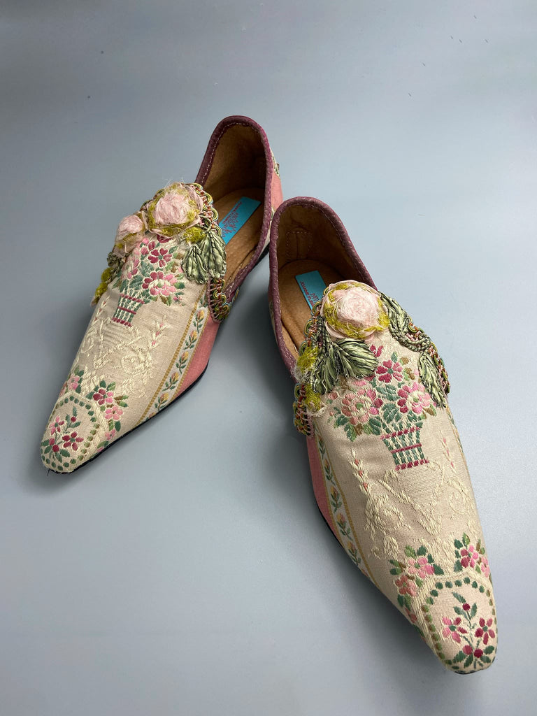 Dusty pink and cream silk pointed toe shoes with timeworn ribbon roses in the Georgian style. Embellished with antique braids. Bohemian styles sustainably created from antique textiles by Pavilion Parade.