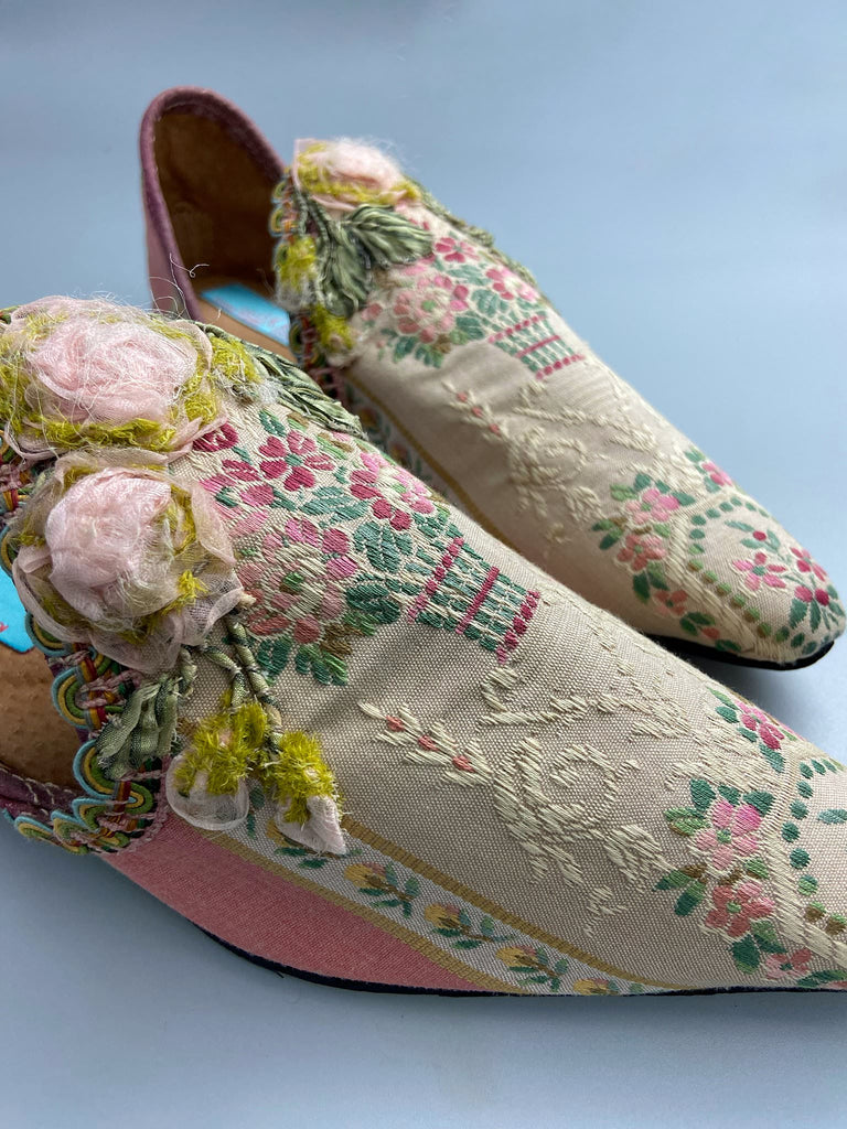 Dusty pink and cream silk pointed toe shoes with timeworn ribbon roses in the Georgian style. Embellished with antique braids. Bohemian styles sustainably created from antique textiles by Pavilion Parade.
