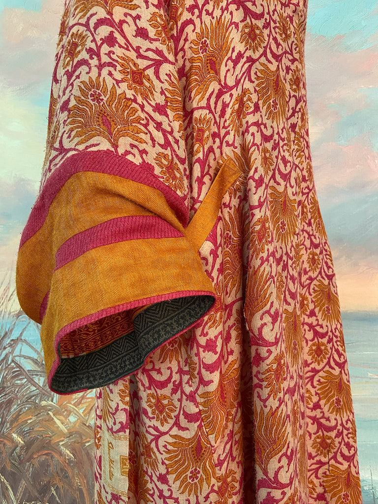 Saffron and hot pink fine wool dressing robe lined with silk. Wide sleeves, patch pockets and tassel sash belt. Bohemian styles sustainably created from antique and vintage textiles by the Pavilion Parade studio.