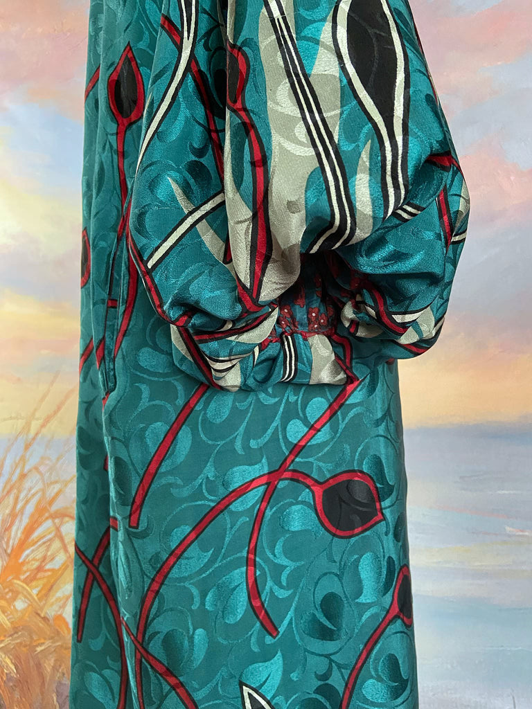 Relaxed fit silk crepe shift dress with full gathered long sleeves, scoop neck and pockets. Teal green with a bold print in black, red, and white. Sustainably created from vintage and antique textiles by the Pavilion Parade studio.
