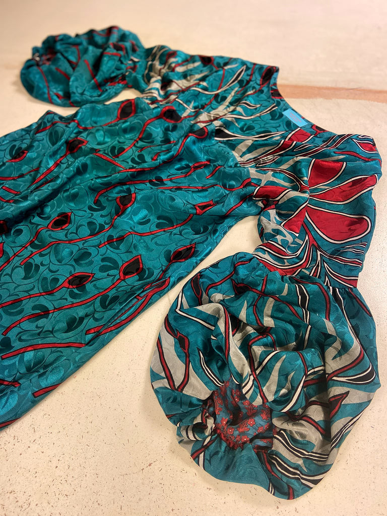 Relaxed fit silk crepe shift dress with full gathered long sleeves, scoop neck and pockets. Teal green with a bold print in black, red, and white. Sustainably created from vintage and antique textiles by the Pavilion Parade studio.