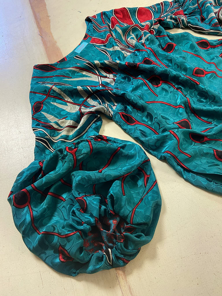 Relaxed fit silk crepe shift dress with full gathered long sleeves, scoop neck and pockets. Teal green with a bold print in black, red, and white. Sustainably created from vintage and antique textiles by the Pavilion Parade studio.
