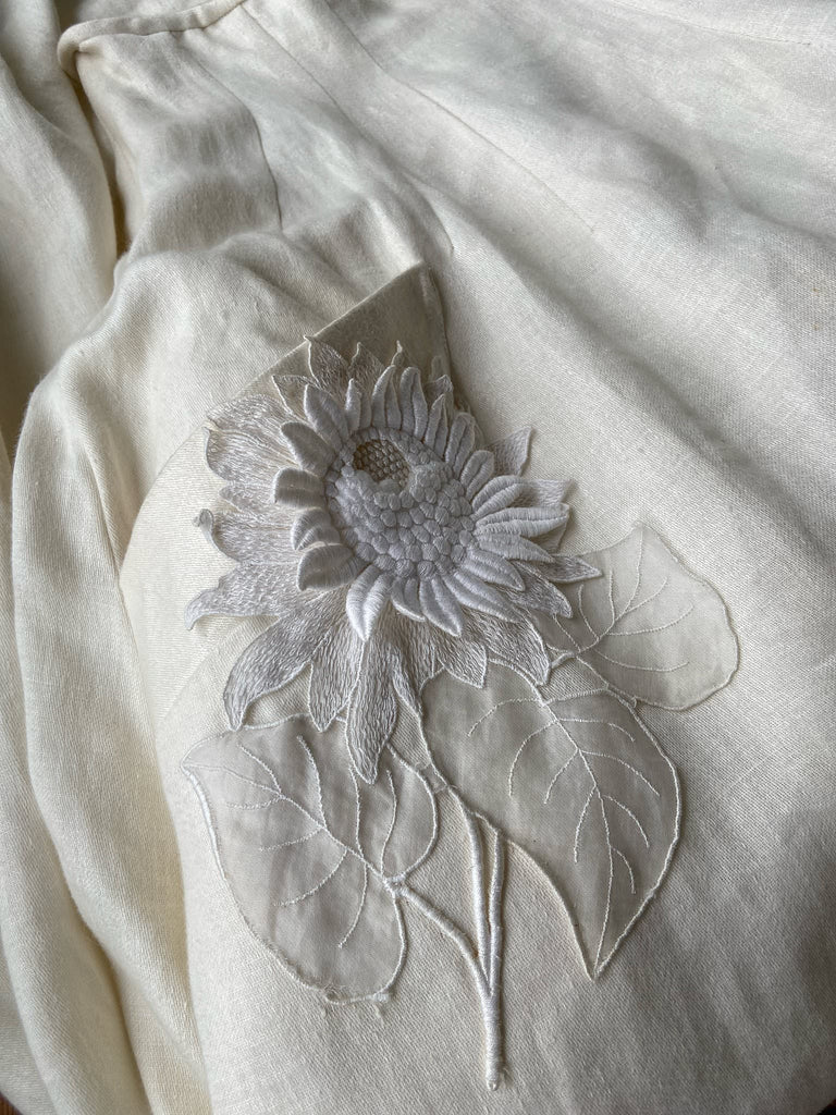 Ivory linen Edwardian style high waisted long skirt with high waist and antique embroidered sunflower appliqués on the deep pockets. Bohemian style from Pavilion Parade.