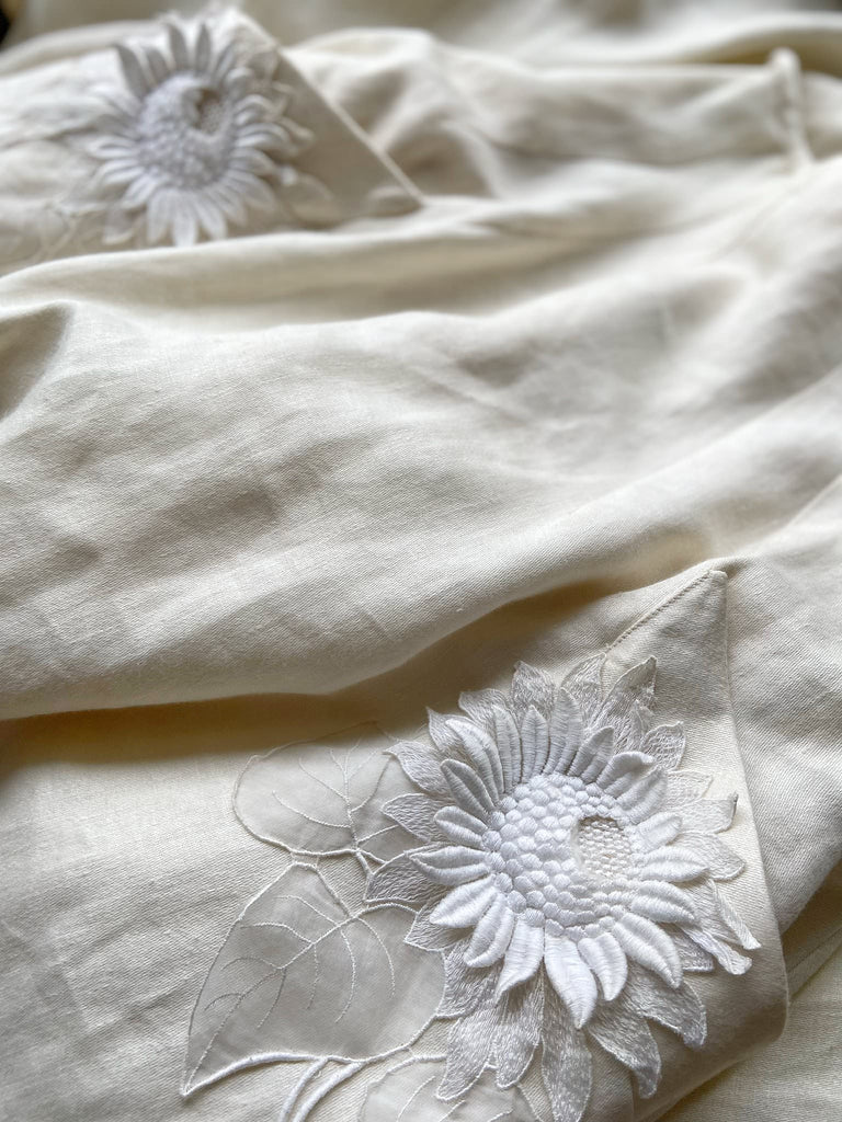 Ivory linen Edwardian style high waisted long skirt with high waist and antique embroidered sunflower appliqués on the deep pockets. Bohemian style from Pavilion Parade.