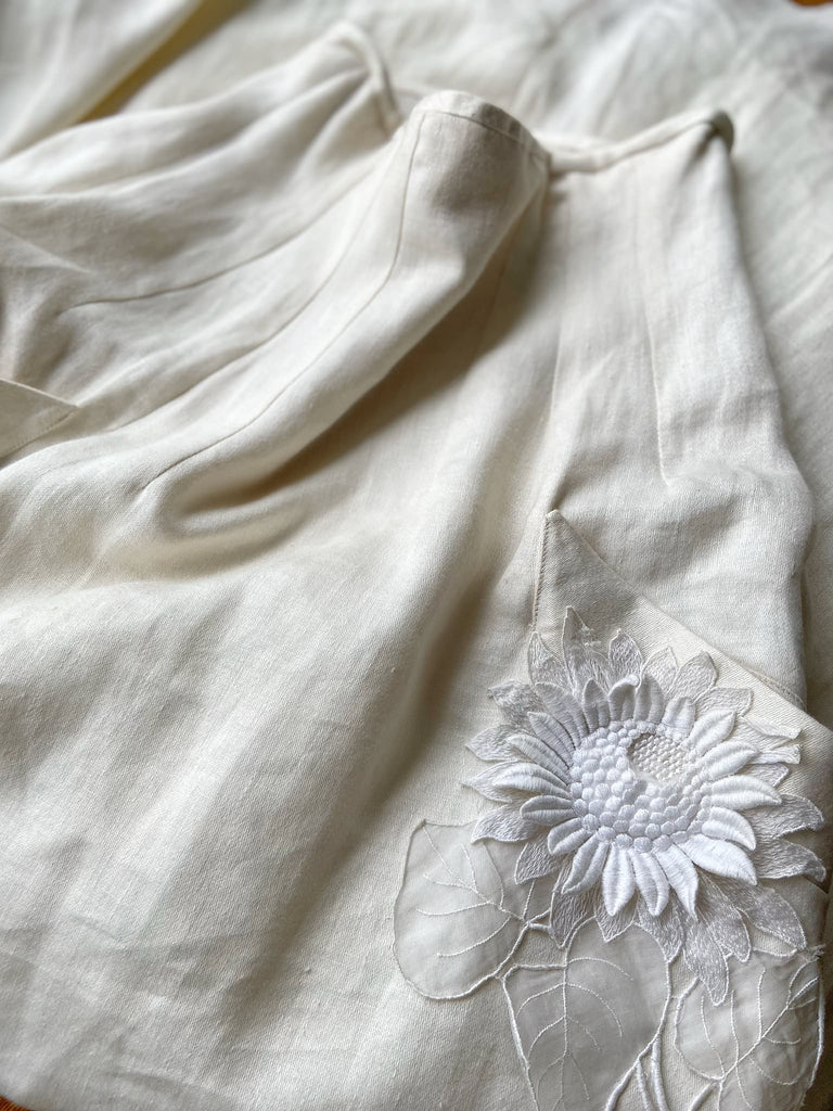 Ivory linen Edwardian style high waisted long skirt with high waist and antique embroidered sunflower appliqués on the deep pockets. Bohemian style from Pavilion Parade.