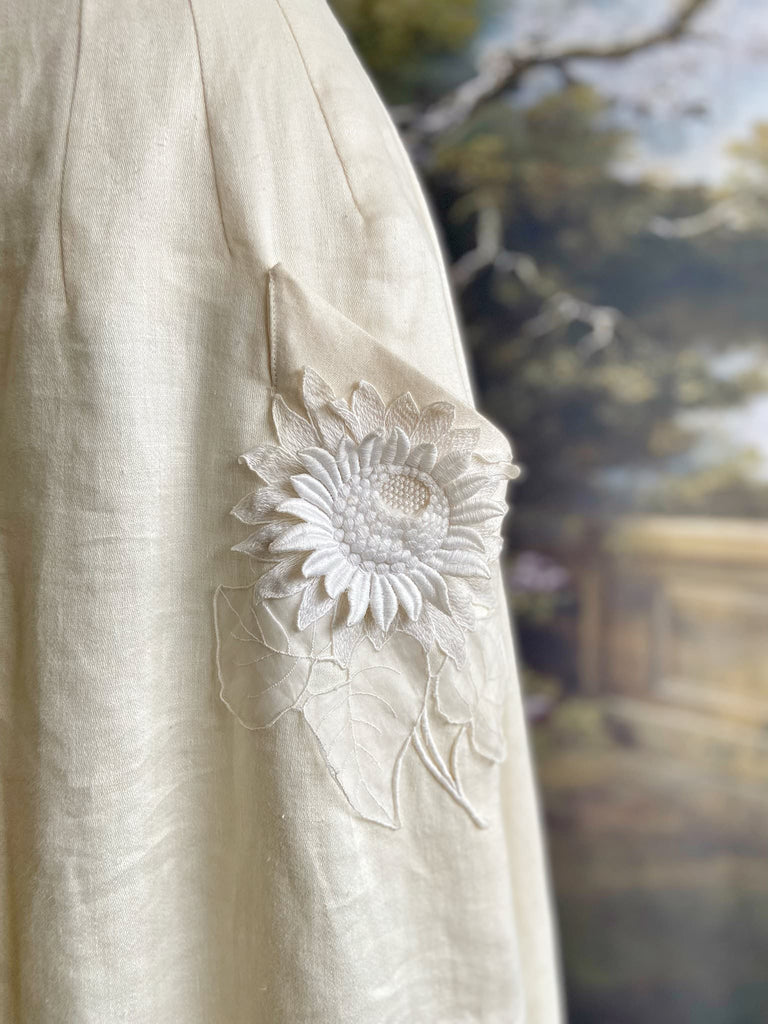 Ivory linen Edwardian style high waisted long skirt with high waist and antique embroidered sunflower appliqués on the deep pockets. Bohemian style from Pavilion Parade.