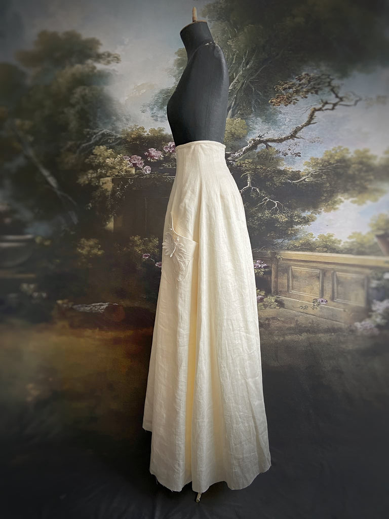 Ivory linen Edwardian style high waisted long skirt with high waist and antique embroidered sunflower appliqués on the deep pockets. Bohemian style from Pavilion Parade.