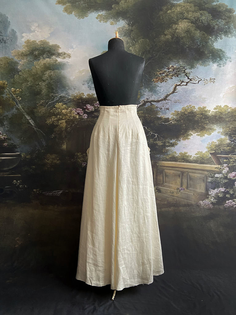 Ivory linen Edwardian style high waisted long skirt with high waist and antique embroidered sunflower appliqués on the deep pockets. Bohemian style from Pavilion Parade.