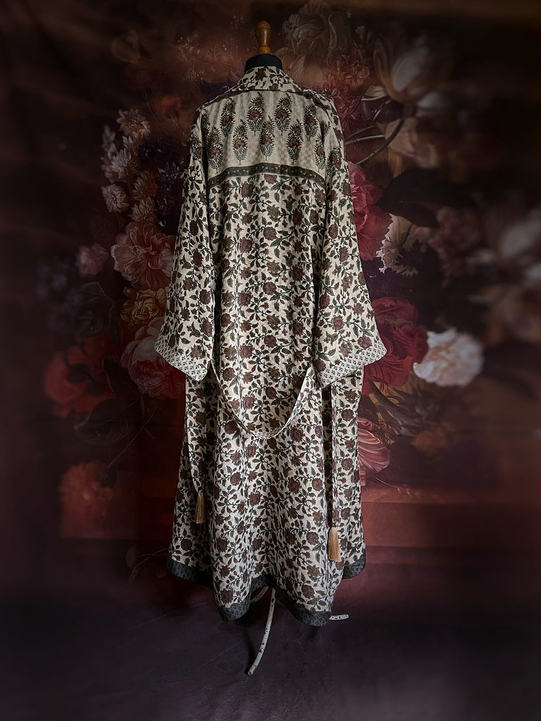 Chestnut brown and olive green fine wool dressing robe or duster coat with a design of Indienne florals. Wide sleeves, deep pockets, tassel sash. Lined in printed silk. Luxury bohemian style sustainably created in the UK from antique and vintage textiles by the Pavilion Parade studio.