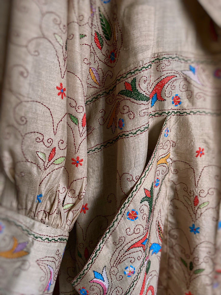 Circus hand embroidered kantha silk robe with balloon sleeves, oversize patch pockets and tassel sash.  Shades of azure blue, daffodil yellow, leaf green, orange  and pink on a warm honey ground. Lined in printed floral silk. Created from antique and vintage textiles by Pavilion Parade.