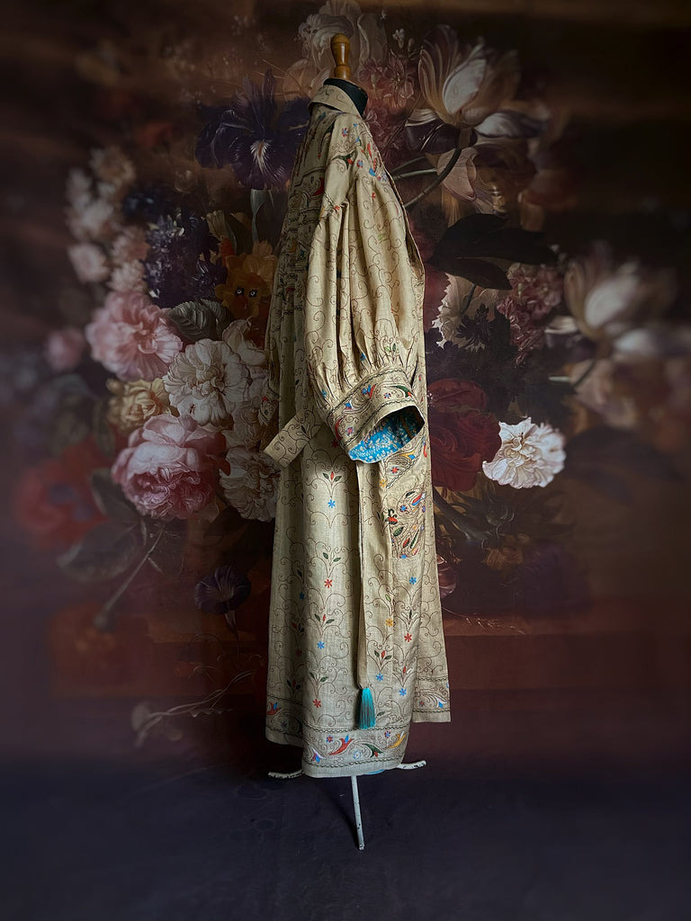 Circus hand embroidered kantha silk robe with balloon sleeves, oversize patch pockets and tassel sash.  Shades of azure blue, daffodil yellow, leaf green, orange  and pink on a warm honey ground. Lined in printed floral silk. Created from antique and vintage textiles by Pavilion Parade.