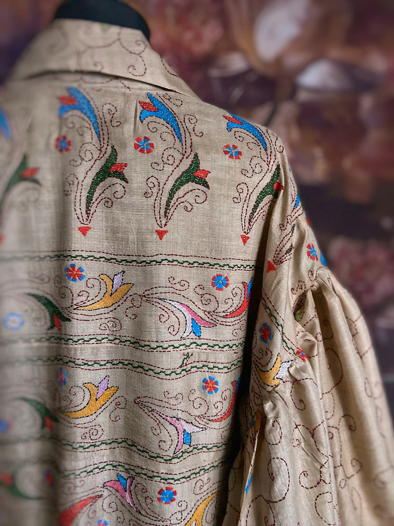 Circus hand embroidered kantha silk robe with balloon sleeves, oversize patch pockets and tassel sash.  Shades of azure blue, daffodil yellow, leaf green, orange  and pink on a warm honey ground. Lined in printed floral silk. Created from antique and vintage textiles by Pavilion Parade.