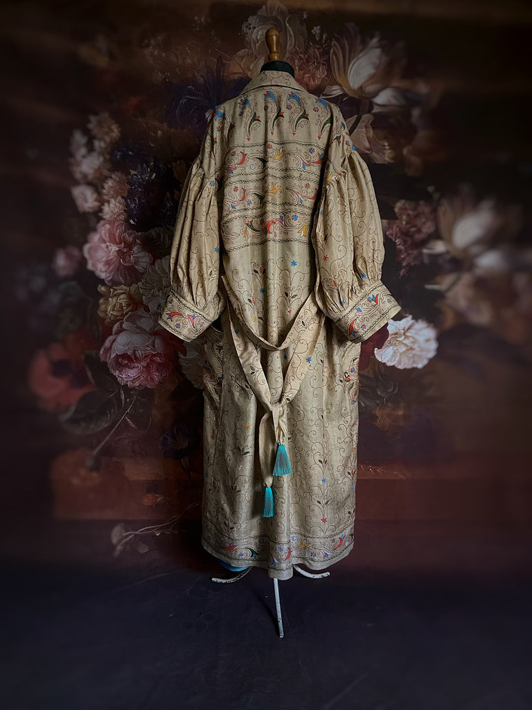 Circus hand embroidered kantha silk robe with balloon sleeves, oversize patch pockets and tassel sash.  Shades of azure blue, daffodil yellow, leaf green, orange  and pink on a warm honey ground. Lined in printed floral silk. Created from antique and vintage textiles by Pavilion Parade.