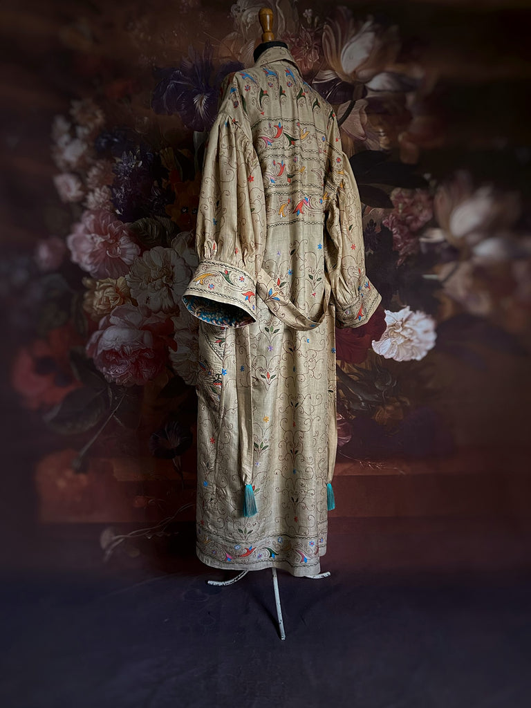 Circus hand embroidered kantha silk robe with balloon sleeves, oversize patch pockets and tassel sash.  Shades of azure blue, daffodil yellow, leaf green, orange  and pink on a warm honey ground. Lined in printed floral silk. Created from antique and vintage textiles by Pavilion Parade.