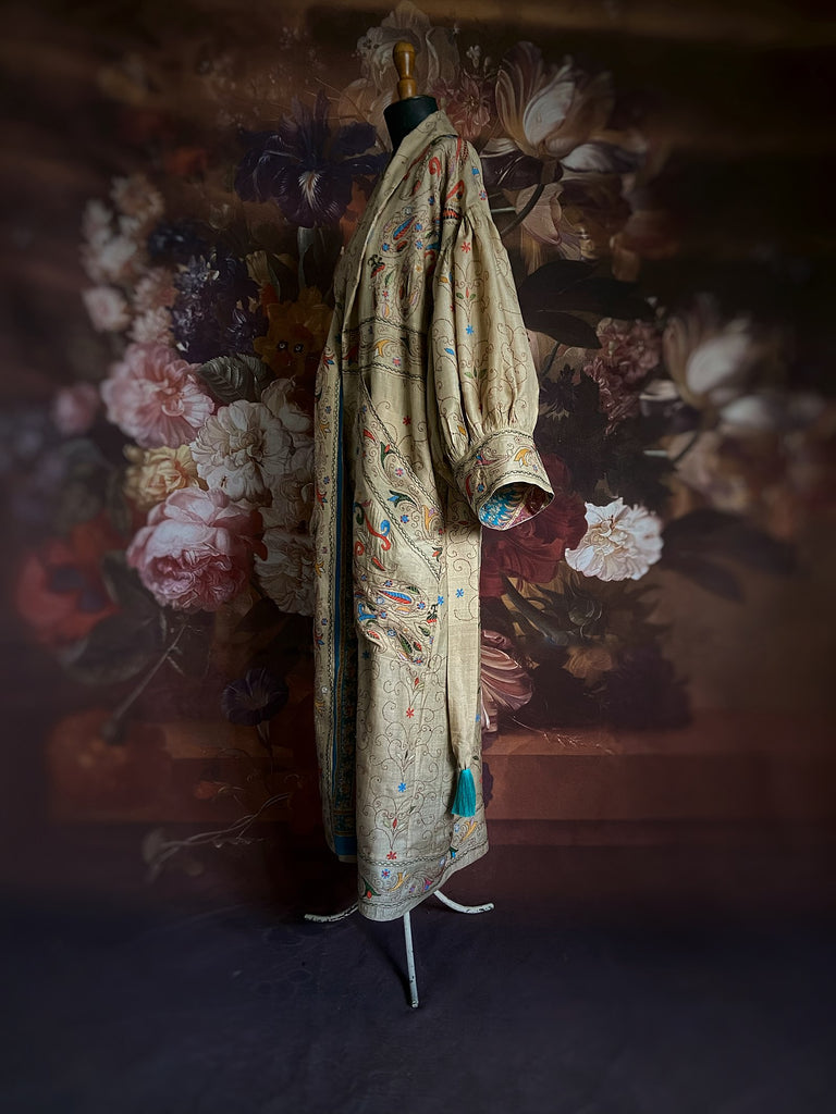 Circus hand embroidered kantha silk robe with balloon sleeves, oversize patch pockets and tassel sash.  Shades of azure blue, daffodil yellow, leaf green, orange  and pink on a warm honey ground. Lined in printed floral silk. Created from antique and vintage textiles by Pavilion Parade.
