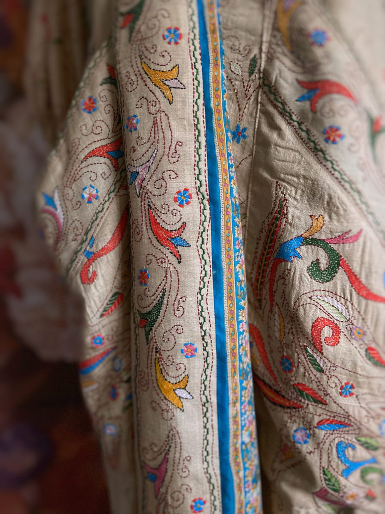 Circus hand embroidered kantha silk robe with balloon sleeves, oversize patch pockets and tassel sash.  Shades of azure blue, daffodil yellow, leaf green, orange  and pink on a warm honey ground. Lined in printed floral silk. Created from antique and vintage textiles by Pavilion Parade.