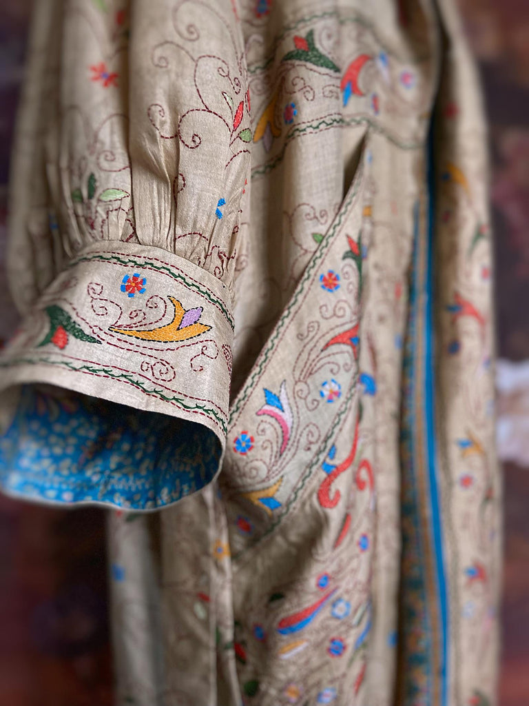 Circus hand embroidered kantha silk robe with balloon sleeves, oversize patch pockets and tassel sash.  Shades of azure blue, daffodil yellow, leaf green, orange  and pink on a warm honey ground. Lined in printed floral silk. Created from antique and vintage textiles by Pavilion Parade.