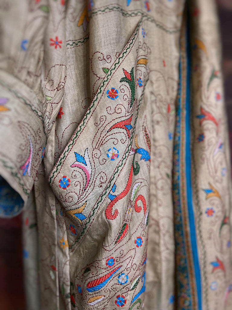 Circus hand embroidered kantha silk robe with balloon sleeves, oversize patch pockets and tassel sash.  Shades of azure blue, daffodil yellow, leaf green, orange  and pink on a warm honey ground. Lined in printed floral silk. Created from antique and vintage textiles by Pavilion Parade.