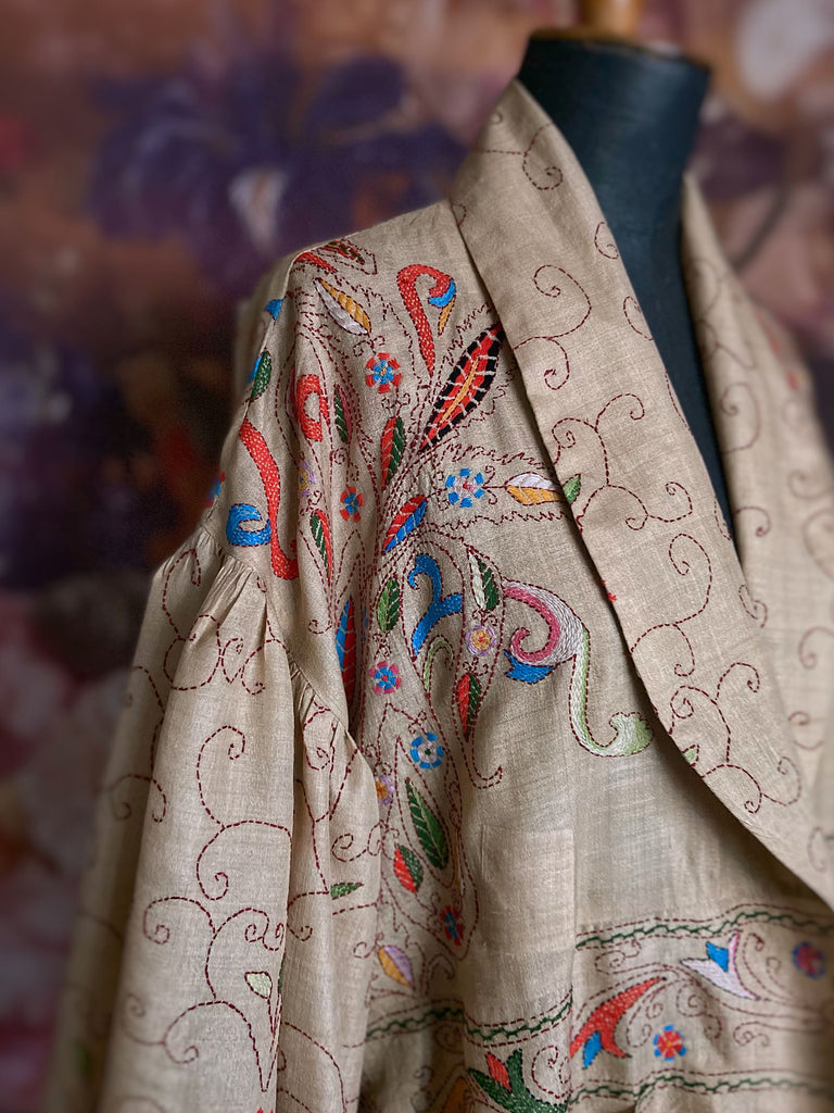 Circus hand embroidered kantha silk robe with balloon sleeves, oversize patch pockets and tassel sash.  Shades of azure blue, daffodil yellow, leaf green, orange  and pink on a warm honey ground. Lined in printed floral silk. Created from antique and vintage textiles by Pavilion Parade.