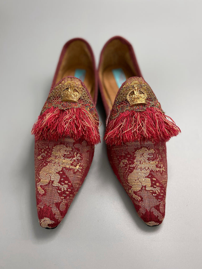 Dark red French brocade slipper shoes with a heraldic design of lions rampant, embellished with early 1800s Florentine silk tassel fringe and aged toleware crowns. Created from antique textiles by Pavilion Parade