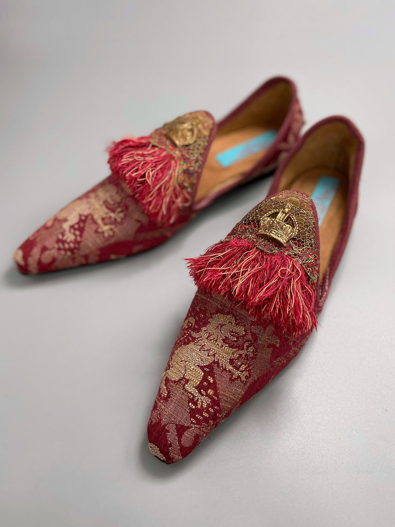 Dark red French brocade slipper shoes with a heraldic design of lions rampant, embellished with early 1800s Florentine silk tassel fringe and aged toleware crowns. Created from antique textiles by Pavilion Parade