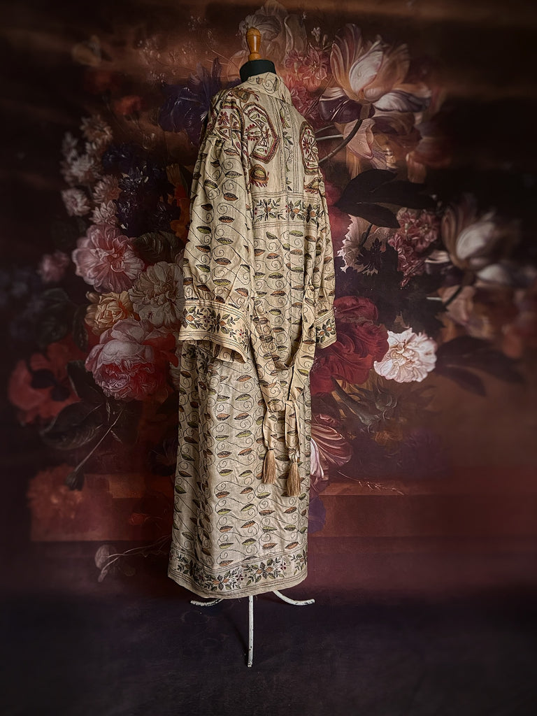 Hand embroidered kantha silk dressing robe or duster coat in an antique ivory shade with leaf green, wine red and chestnut floral embroidery. Wide sleeves, deep pockets and tassel sash belt. Created from vintage and antique textiles by the Pavilion Parade studio.