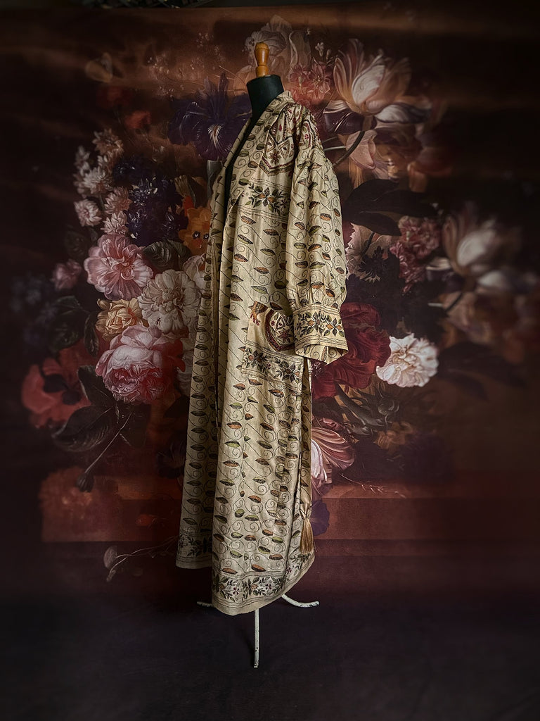 Hand embroidered kantha silk dressing robe or duster coat in an antique ivory shade with leaf green, wine red and chestnut floral embroidery. Wide sleeves, deep pockets and tassel sash belt. Created from vintage and antique textiles by the Pavilion Parade studio.