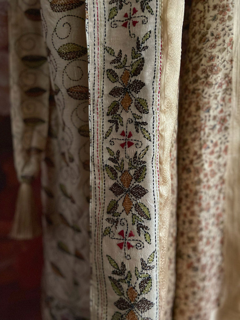 Hand embroidered kantha silk dressing robe or duster coat in an antique ivory shade with leaf green, wine red and chestnut floral embroidery. Wide sleeves, deep pockets and tassel sash belt. Created from vintage and antique textiles by the Pavilion Parade studio.