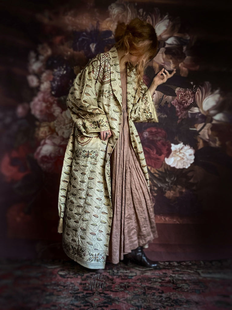 Hand embroidered kantha silk dressing robe or duster coat in an antique ivory shade with leaf green, wine red and chestnut floral embroidery. Wide sleeves, deep pockets and tassel sash belt. Created from vintage and antique textiles by the Pavilion Parade studio.