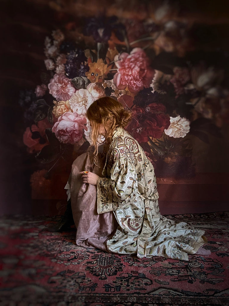 Hand embroidered kantha silk dressing robe or duster coat in an antique ivory shade with leaf green, wine red and chestnut floral embroidery. Wide sleeves, deep pockets and tassel sash belt. Created from vintage and antique textiles by the Pavilion Parade studio.