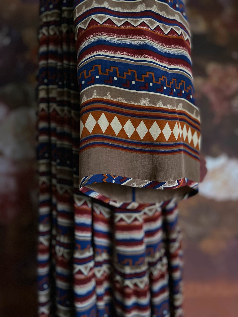 Multi coloured geometric striped silk crepe maxi dress in lapiz blue, cinnabar orange and chilli red. Tassel drawstring neckline, pockets and flowing tiered skirt. Bohemian style created from vintage textiles by the Pavilion Parade Studio.
