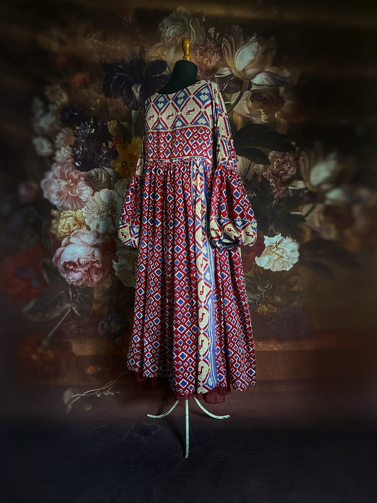 Ruby red and Persian blue printed ikat fine cotton muslin dress with full balloon sleeves, pockets and tiered hem. Bohemian style from the Pavilion Parade studio.