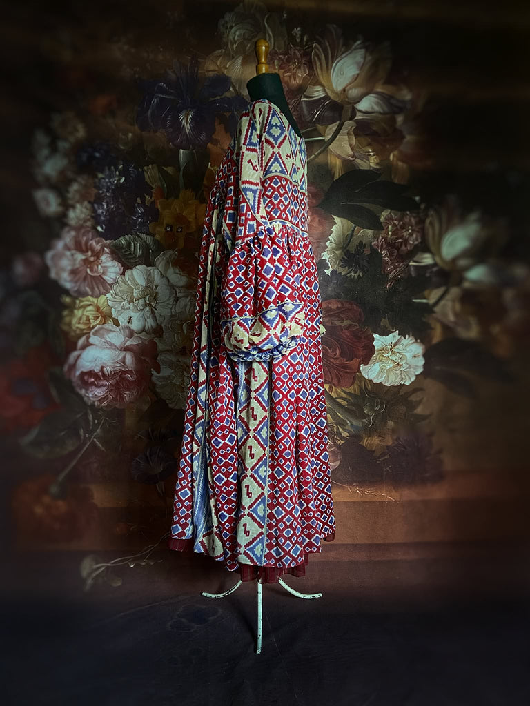 Ruby red and Persian blue printed ikat fine cotton muslin dress with full balloon sleeves, pockets and tiered hem. Bohemian style from the Pavilion Parade studio.