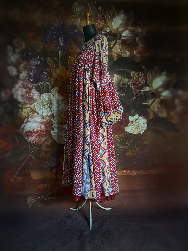 Ruby red and Persian blue printed ikat fine cotton muslin dress with full balloon sleeves, pockets and tiered hem. Bohemian style from the Pavilion Parade studio.