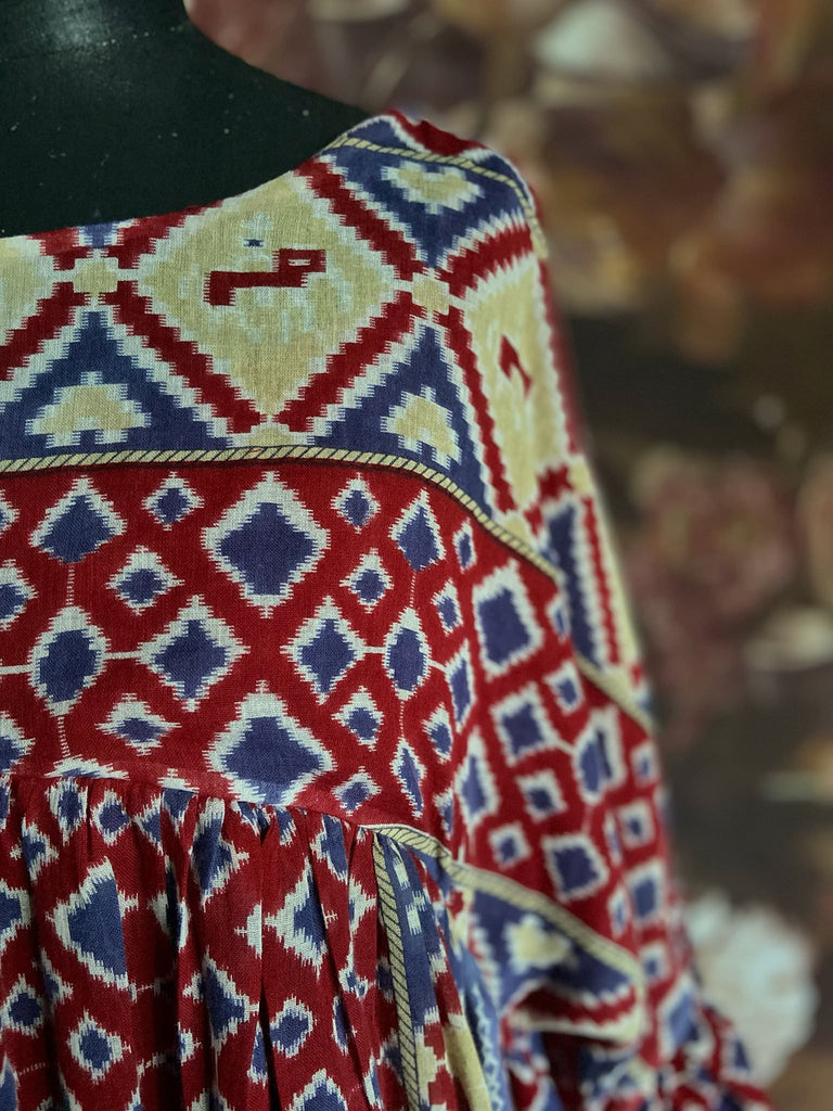 Ruby red and Persian blue printed ikat fine cotton muslin dress with full balloon sleeves, pockets and tiered hem. Bohemian style from the Pavilion Parade studio.
