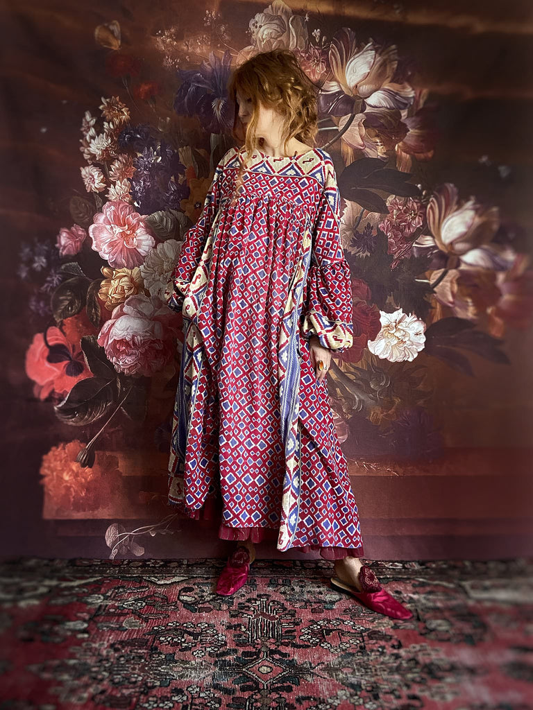 Ruby red and Persian blue printed ikat fine cotton muslin dress with full balloon sleeves, pockets and tiered hem. Bohemian style from the Pavilion Parade studio.