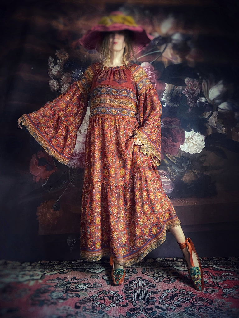 Vibrant floral silk georgette maxi dress in red, saffron yellow and cobalt blue, with long pagoda sleeves and tiered skirt. A Brighton Bohemian sustainable piece created from vintage and antique textiles for Pavilion Parade